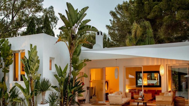 Een modern huis met een zwembad, terras en weelderige begroeiing.