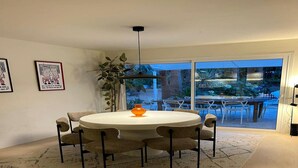 Een eetgedeelte met een ronde tafel, zes stoelen en een oranje vaas in het midden.