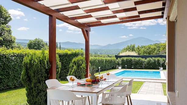 A covered outdoor dining area with a view of a swimming pool and mountains. - Gorgeous home in Lucane (Lucane)