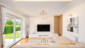 A modern living room with a large flat-screen TV, a sofa, and a dining table. - Gorgeous home in Lucane (Lucane)