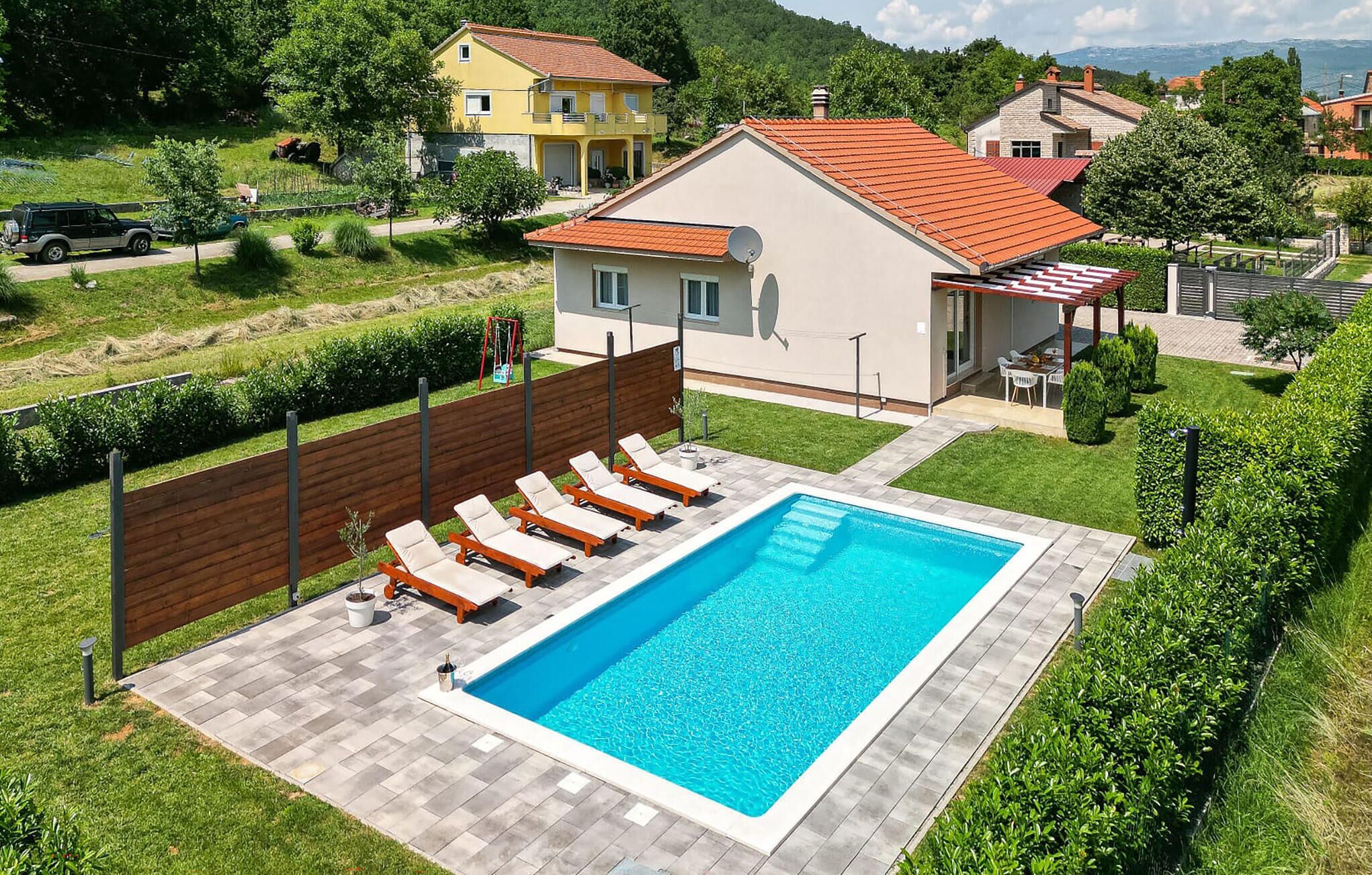 A residential property with a swimming pool, a fenced garden, and a view of surrounding houses.