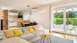 A modern living room with a sofa, a coffee table, and a dining area with chairs and a table. There is a sliding glass door leading to an outdoor patio. - Gorgeous home in Lucane (Lucane)