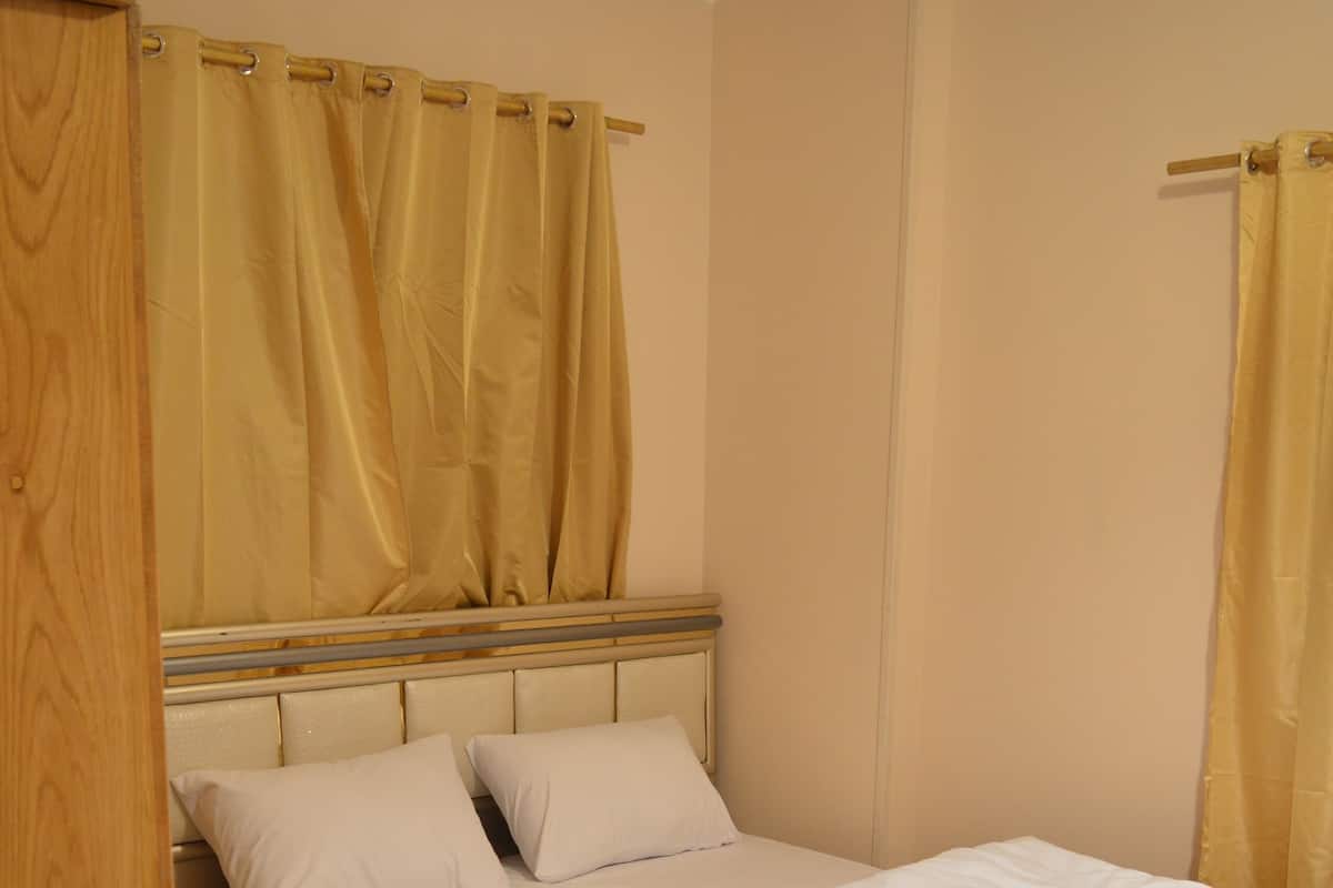 A neatly made bed with white linens, a wooden headboard, and a small bedside table with a lamp.