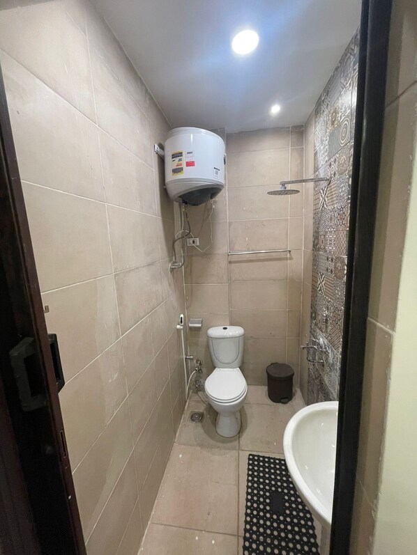 A small, tiled bathroom with a toilet, a bidet, and a shower.