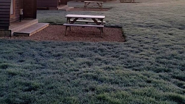 A row of rustic, arched cabins with picnic tables in a frosty field. - Rural Cabin in the Lincolnshire Countryside (Grantham)