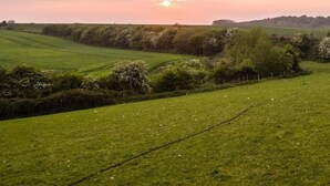 A rural landscape with rolling green fields and a sunset in the distance. - Rural Cabin in the Lincolnshire Countryside (Grantham)