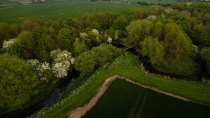 An aerial view of a rural landscape with fields, a river, and a bridge.