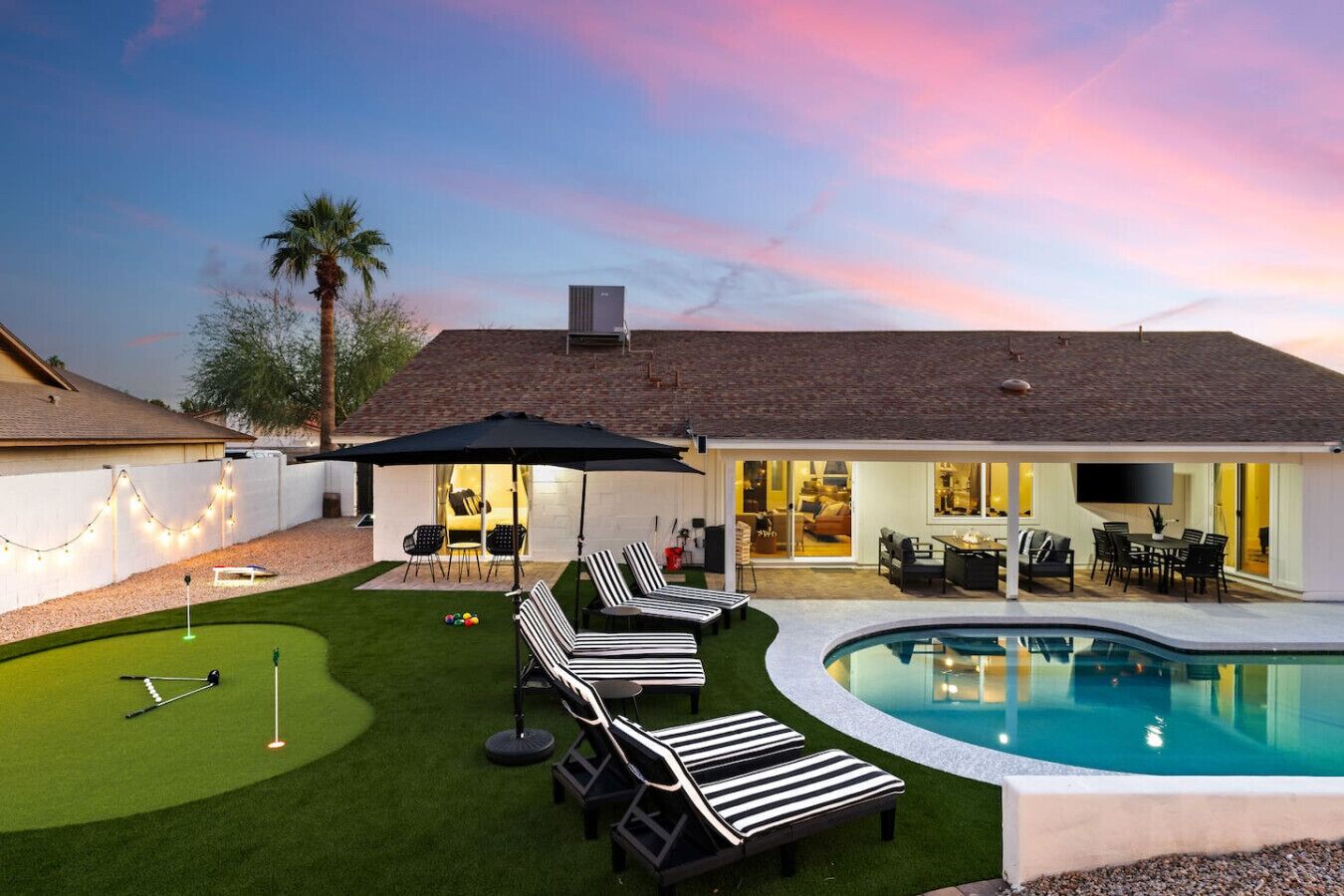 Une maison moderne dotée d’une piscine, d’un patio avec des chaises longues et d’une pelouse bien entretenue.