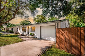 A single-story mobile home with a garage, a front porch with a bench, and a wooden fence.