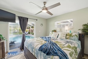 A bedroom with a bed, a ceiling fan, a window, and a view of an outdoor swimming pool.