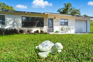 A modern two-story house with a garage, a well-maintained lawn, and a decorative sculpture in the foreground.