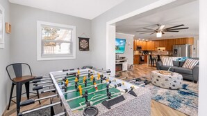 A living room with a foosball table, a sofa, and a television.