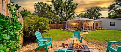 A backyard with a fire pit, outdoor seating, and a covered patio area.