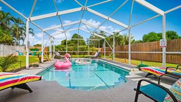 A covered outdoor swimming pool with lounge chairs and a flamingo float.