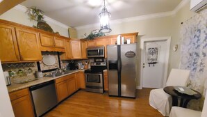 A compact kitchen with wooden cabinets, stainless steel appliances, and a white door.