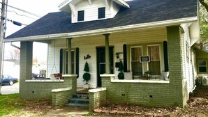 A two-story house with a porch, a small front yard, and a mailbox.