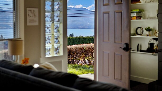 A room with a view of a lake and mountains through a door.