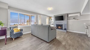 A modern living room with a grey sofa, a small armchair, and a fireplace.