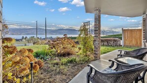 A patio with outdoor furniture, a view of a lake, and a distant mountain range.