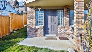 A residential house with a brick exterior, a gray front door, and a small porch area.