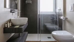 A modern bathroom with a glass shower enclosure, a white sink, and a toilet. - Basic Double Room (Bari)