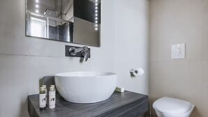 A modern bathroom with a white sink, a mirror, and a toilet. - Single Room (Bari)