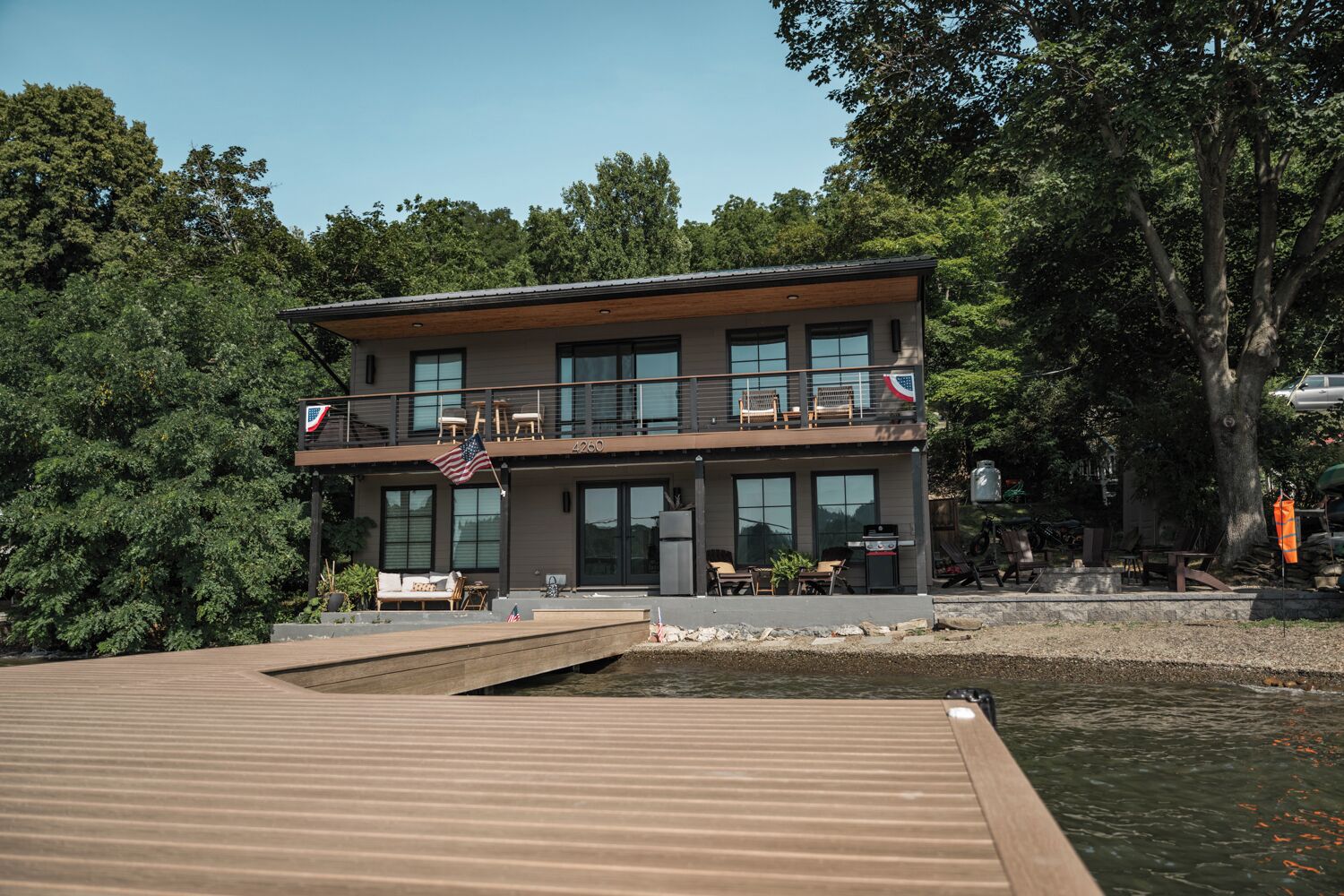 A two-story house with a balcony, a dock, and a flag.