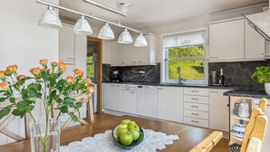 Een moderne keuken met witte kasten, een marmeren aanrechtblad en uitzicht op groen.