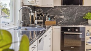 Een moderne keuken met een zwarte marmeren spatwand, roestvrijstalen apparatuur en een wijnrek.