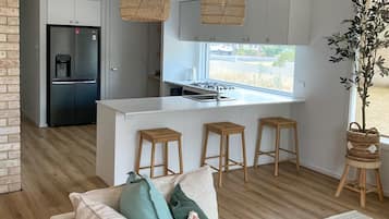 A modern kitchen with white cabinets, a black refrigerator, and a central island with stools.