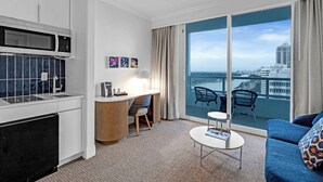 Et moderne hotelværelse med tekøkken, spiseplads og en balkon med udsigt over byen.