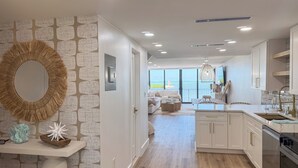 A modern kitchen with white cabinets, a large island, and a view to the outside.