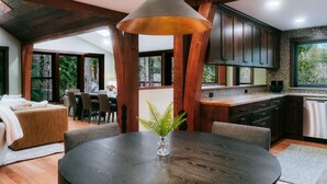 Une cuisine moderne avec des poutres en bois, un coin repas doté d’une table ronde et une vue sur l’extérieur.