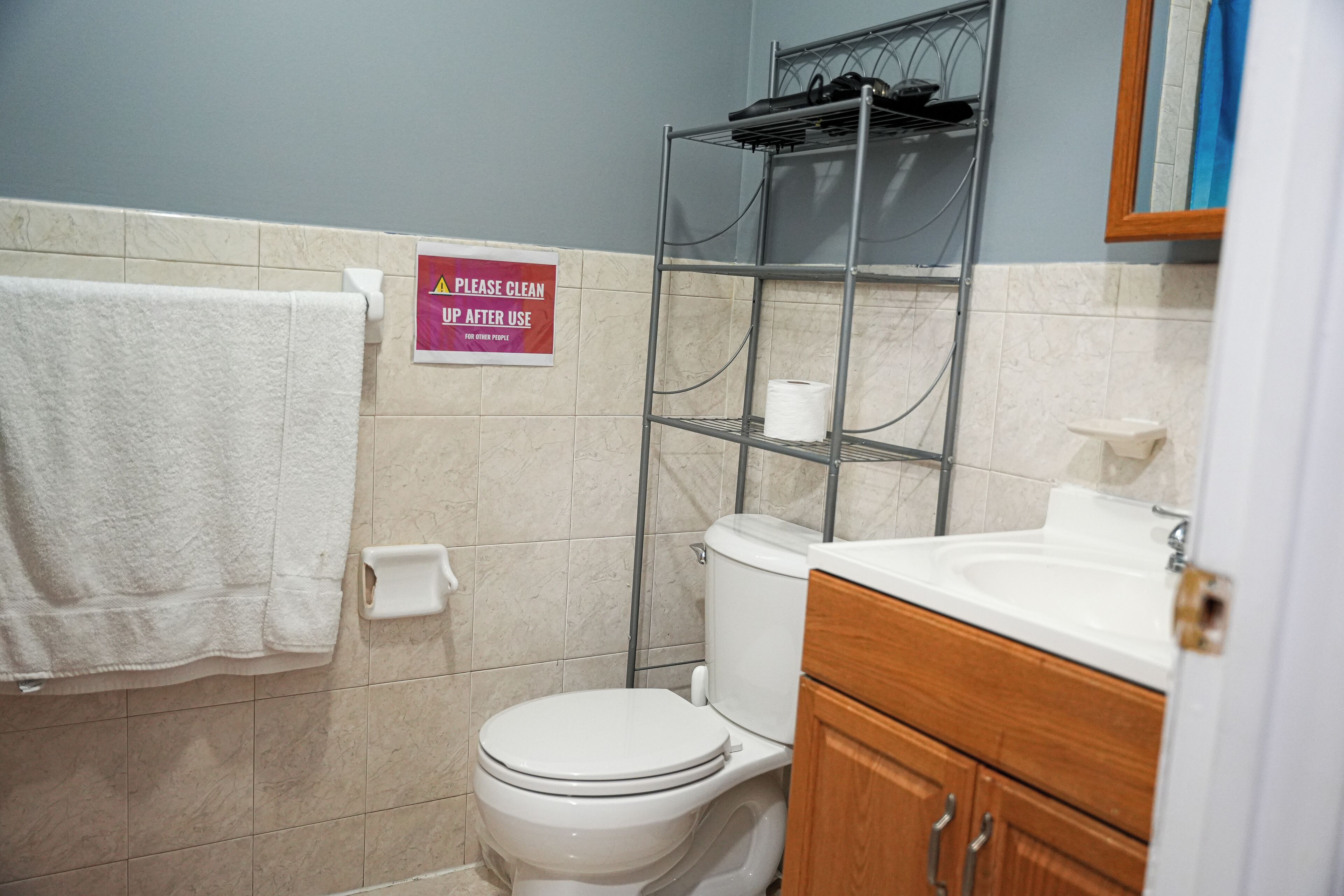 Une salle de bain comprenant des toilettes, un lavabo, un porte-serviettes et une étagère avec des articles de toilette.
