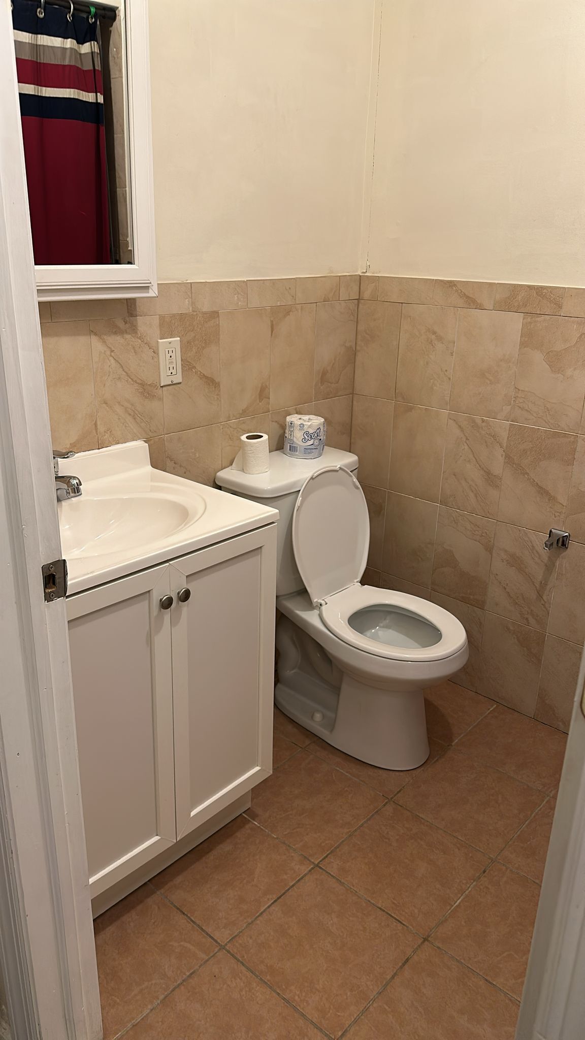 Un baño con inodoro, lavamanos y mueble de almacenamiento.