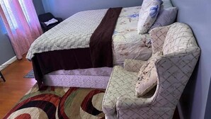 Ein Schlafzimmer mit einem Bett, einem Sessel und einem Teppich mit Muster.