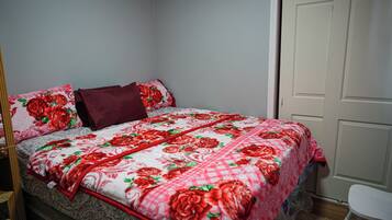 Un dormitorio con una cama, una silla blanca y una puerta cerrada.