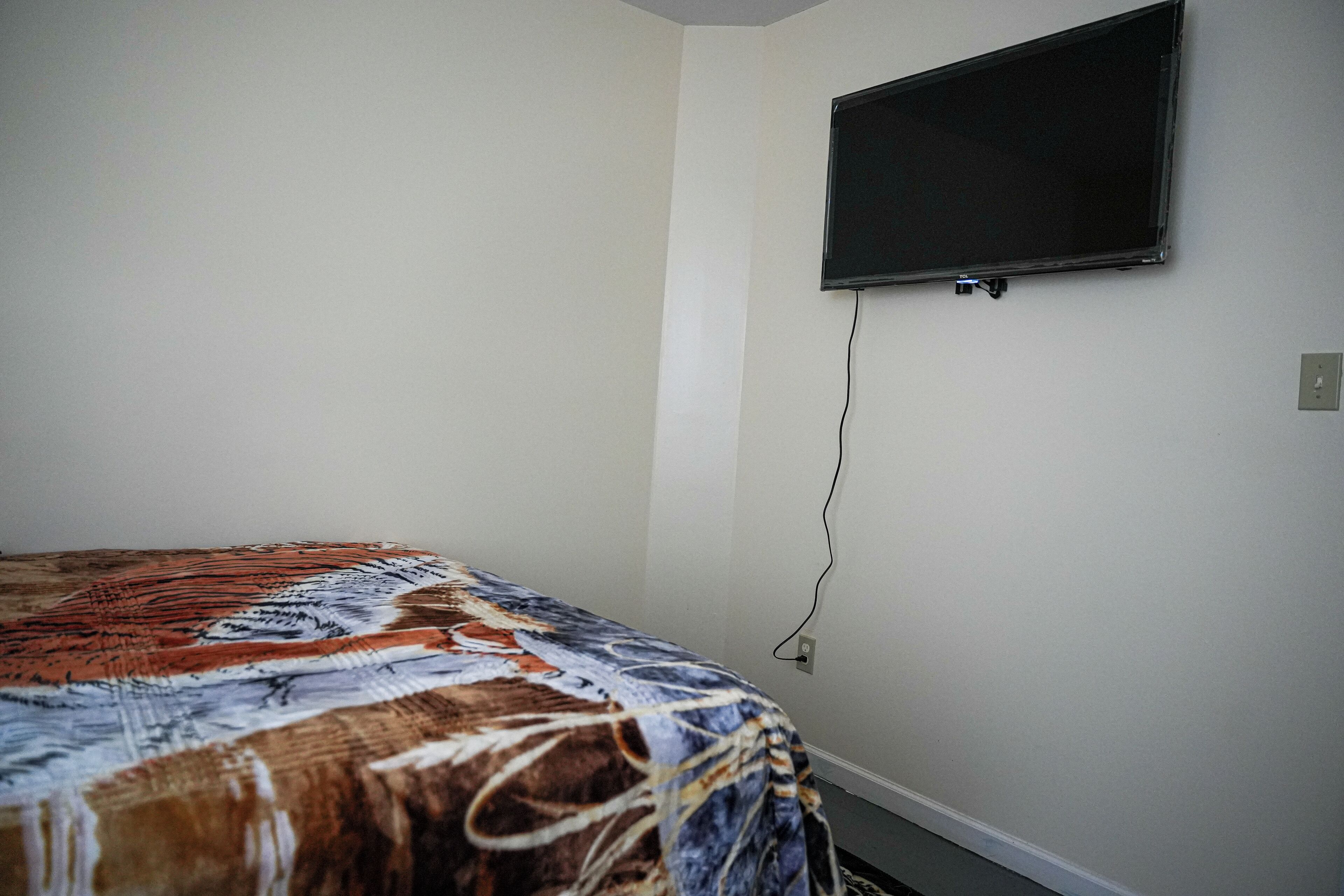 Ein Schlafzimmer mit einem Bett, einem flachbildfernseher an der Wand und einer Steckdose.