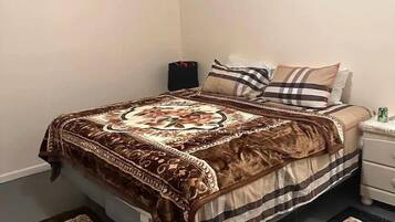 A bedroom with a bed, a nightstand, a lamp, and two rugs.