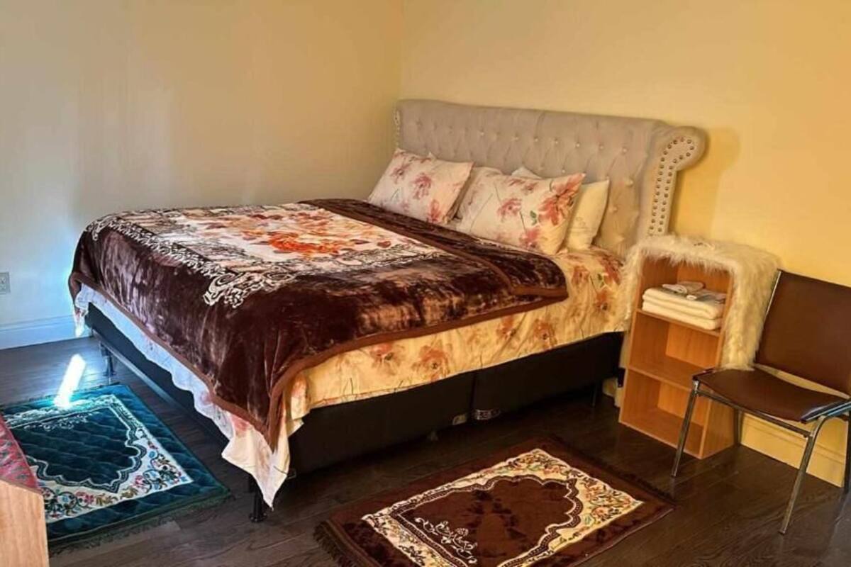 Ein Schlafzimmer mit einem Bett, einem Nachttisch, einem Stuhl und zwei Teppichen.