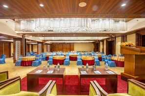 Un salón de conferencias con mesas redondas, sillas azules y una alfombra roja.