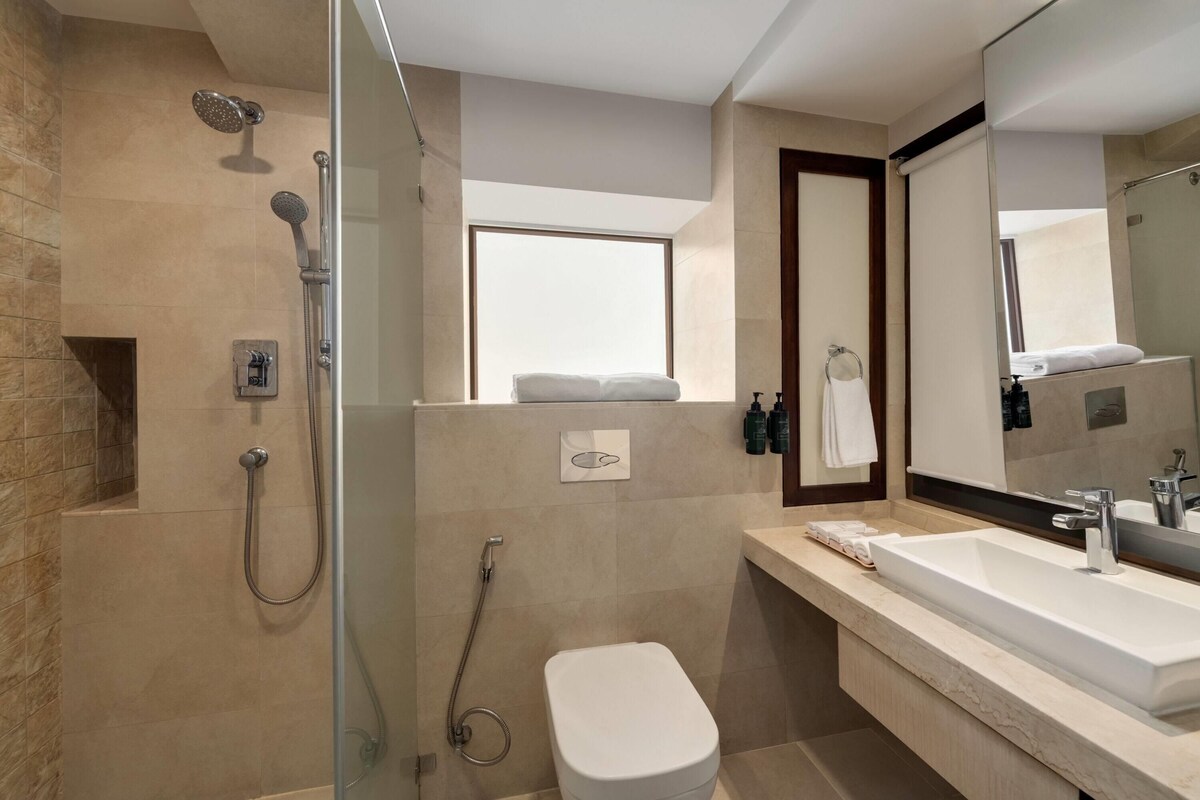 Un bany modern amb dutxa de vidre, un lavabo gran i un vàter.