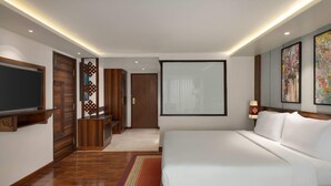 A modern hotel room with a large bed, a flat-screen TV, wooden doors, and artwork on the walls. - Ramada by Wyndham Kathmandu Dhumbarahi (Kathmandu)
