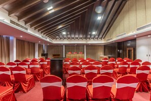 Un salón de conferencias con filas de sillas rojas y un atril al frente.