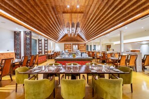 A spacious dining area with long tables and chairs, a central island with a sink, and a wooden ceiling with recessed lighting. - Ramada by Wyndham Kathmandu Dhumbarahi (Kathmandu)