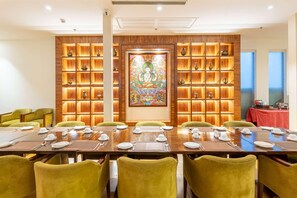 A dining area with a long wooden table set for six, surrounded by green upholstered chairs. - Ramada by Wyndham Kathmandu Dhumbarahi (Kathmandu)