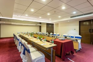Un salón de conferencias con una mesa larga, sillas y un proyector.