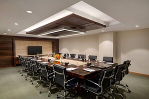 A conference room with a long table, multiple chairs, a flat-screen TV, and a wooden accent wall. - Ramada by Wyndham Kathmandu Dhumbarahi (Kathmandu)