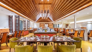A spacious dining area with long tables and chairs, a central island with a sink, and a wooden ceiling with recessed lighting. - Ramada by Wyndham Kathmandu Dhumbarahi (Kathmandu)