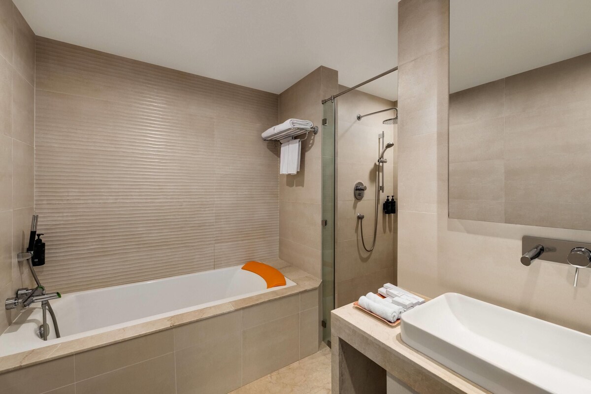 A modern bathroom with a bathtub, shower, and sink.